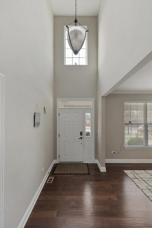 entryway featuring a towering ceiling and dark wood-type flooring