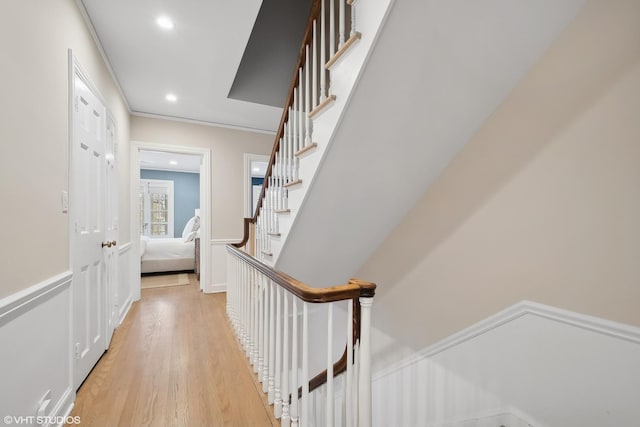 stairs with wood-type flooring and ornamental molding