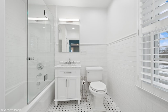 full bathroom featuring tile walls, vanity, shower / bath combination with glass door, and toilet