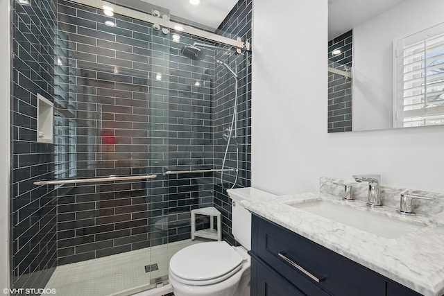 bathroom featuring vanity, a shower with door, and toilet