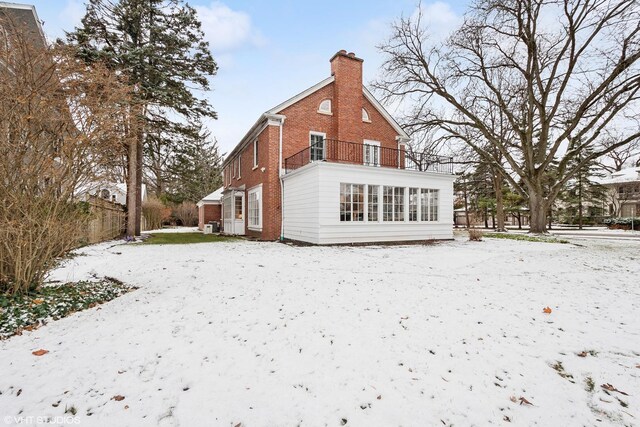 snow covered back of property featuring a balcony