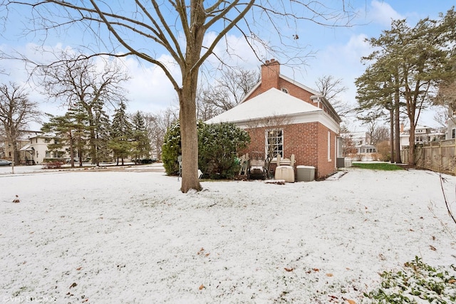 snow covered rear of property featuring central air condition unit