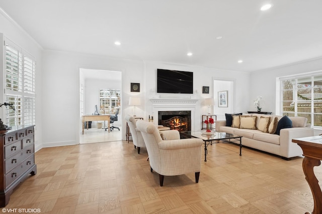 living room with crown molding, plenty of natural light, a premium fireplace, and light parquet floors