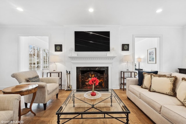 living room featuring hardwood / wood-style flooring, a premium fireplace, and ornamental molding