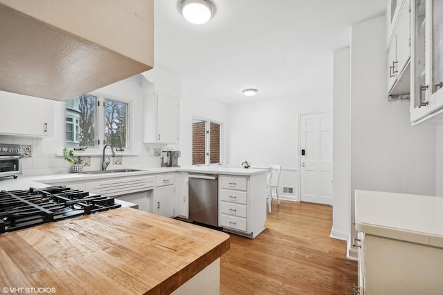 kitchen featuring white cabinetry, dishwasher, sink, and kitchen peninsula