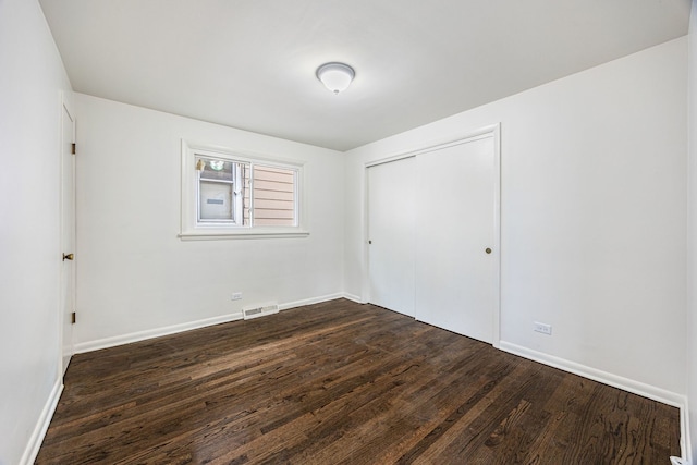 unfurnished bedroom with dark hardwood / wood-style floors and a closet