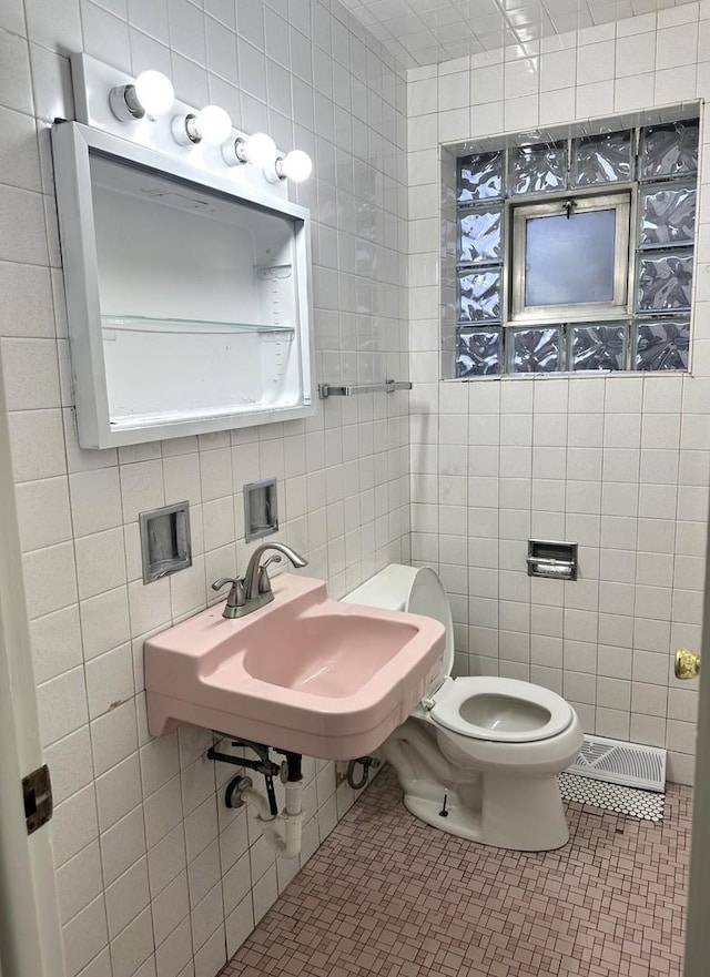 bathroom with tile patterned floors, sink, tile walls, and toilet