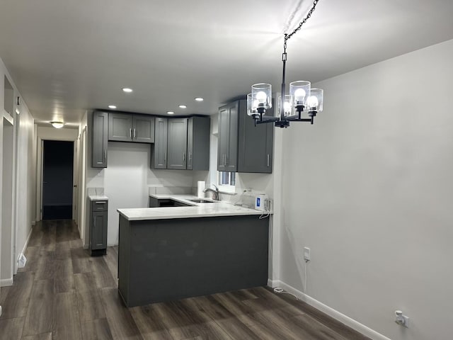 kitchen featuring gray cabinetry, pendant lighting, dark wood-type flooring, sink, and kitchen peninsula