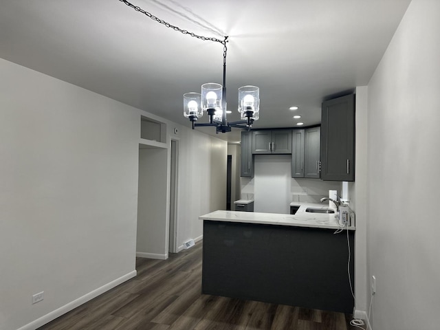 kitchen featuring kitchen peninsula, gray cabinetry, sink, an inviting chandelier, and dark hardwood / wood-style floors