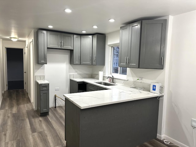 kitchen featuring gray cabinets, light stone countertops, sink, and dark hardwood / wood-style floors