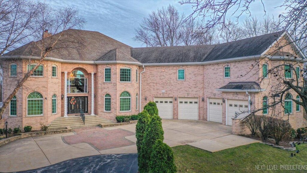 4S241 Meadow Rd, Naperville, IL 60563 - view of front of house with driveway, a chimney, an attached garage, and brick siding
