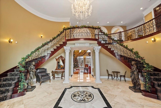 foyer entrance featuring a high ceiling, decorative columns, an inviting chandelier, and ornamental molding