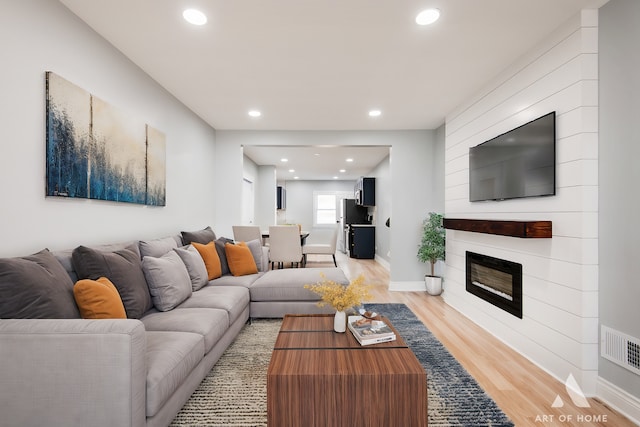 living room featuring a large fireplace and light wood-type flooring