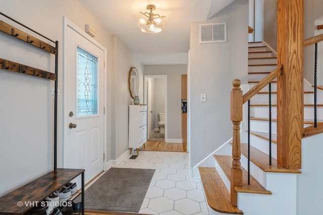 tiled entryway with a chandelier