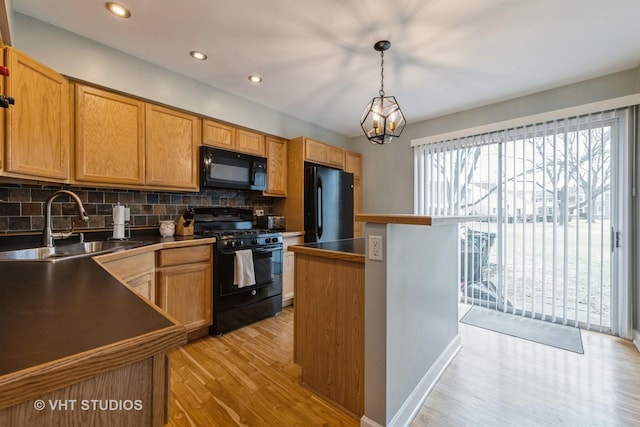 kitchen with pendant lighting, sink, decorative backsplash, a center island, and black appliances