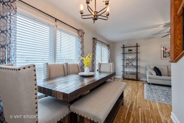 dining room with ceiling fan with notable chandelier and light hardwood / wood-style flooring