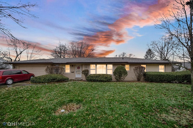 ranch-style home with a garage and a lawn