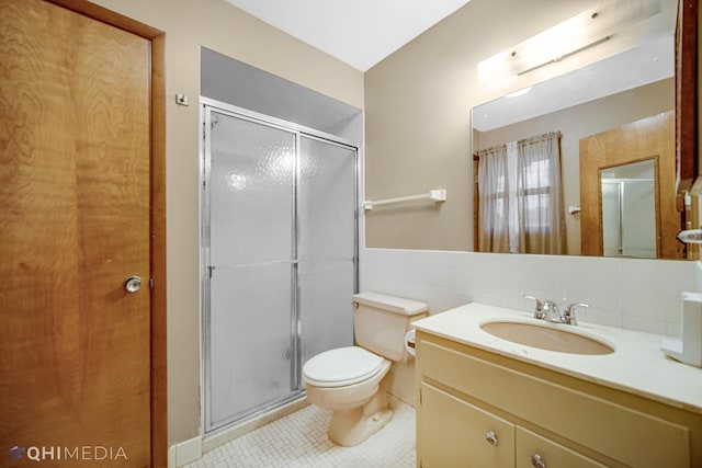 bathroom featuring vanity, a shower with door, toilet, and tile walls