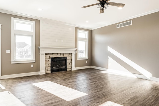 unfurnished living room with ceiling fan, a stone fireplace, dark hardwood / wood-style flooring, and a wealth of natural light