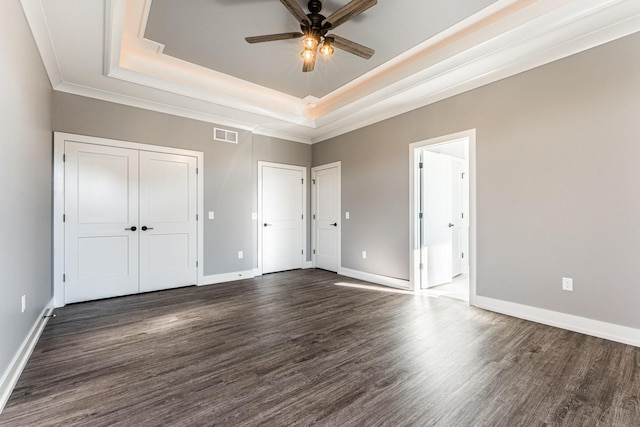 unfurnished bedroom featuring dark hardwood / wood-style floors, a raised ceiling, and ceiling fan