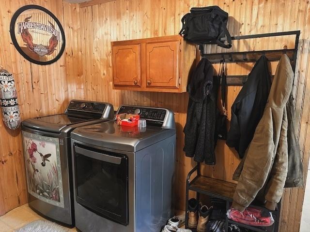 laundry room with separate washer and dryer, wood walls, and cabinets