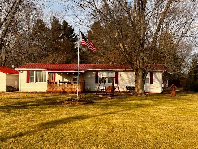 rear view of house with covered porch and a yard