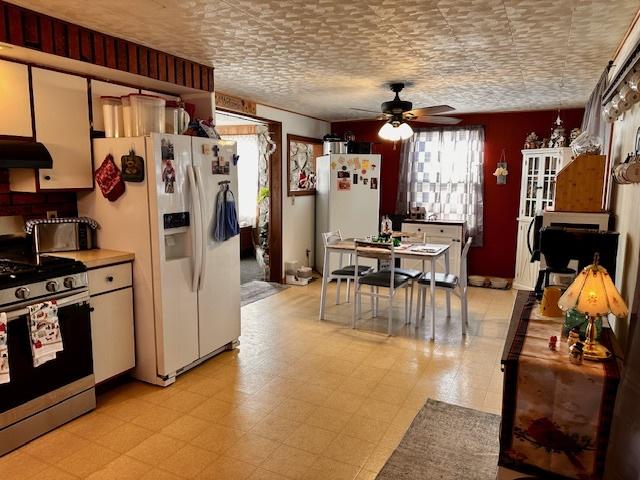 kitchen featuring white refrigerator with ice dispenser, stainless steel range with gas cooktop, plenty of natural light, and exhaust hood