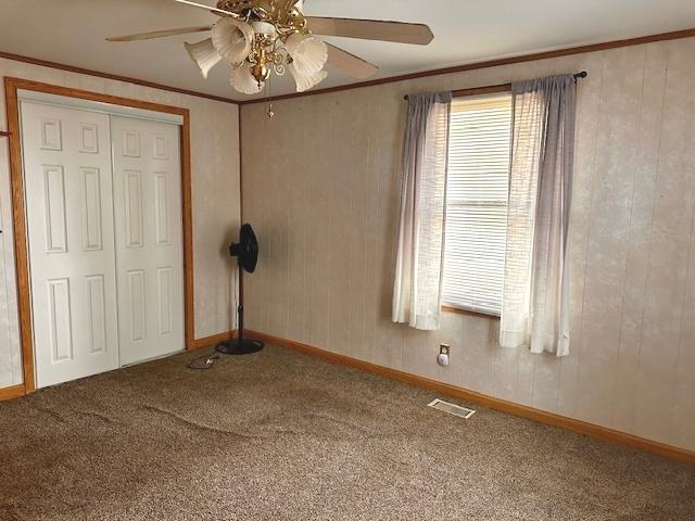 unfurnished bedroom featuring ceiling fan, a closet, carpet floors, and ornamental molding