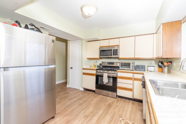 kitchen featuring stainless steel appliances, sink, and light hardwood / wood-style floors