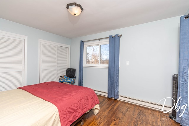 bedroom with dark hardwood / wood-style flooring, a baseboard heating unit, and multiple closets