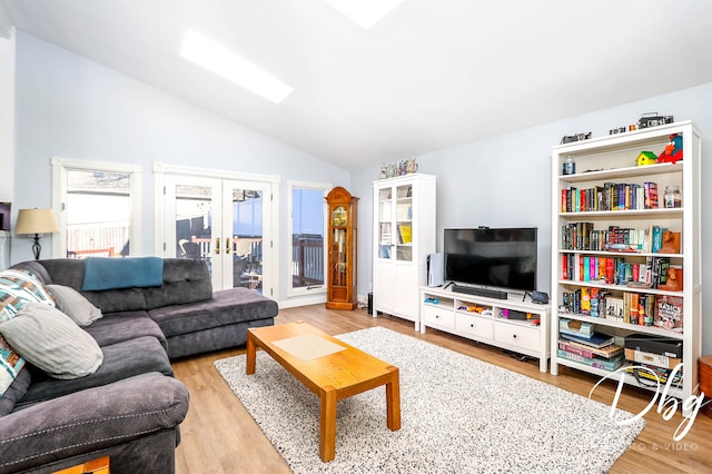 living room featuring vaulted ceiling, french doors, and light hardwood / wood-style floors