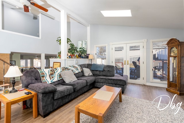 living room featuring french doors, hardwood / wood-style floors, ceiling fan, a skylight, and high vaulted ceiling