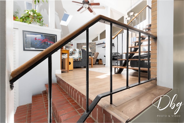 stairway featuring lofted ceiling and ceiling fan with notable chandelier