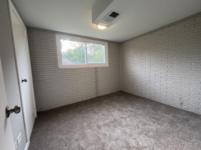 carpeted empty room featuring brick wall