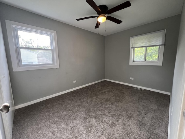 spare room featuring ceiling fan and dark colored carpet