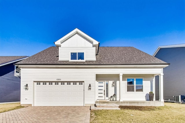 view of front of home featuring a porch, cooling unit, a front yard, and a garage