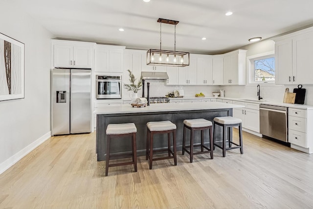 kitchen with stainless steel appliances, a center island, white cabinetry, backsplash, and hanging light fixtures