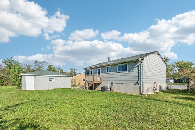 rear view of house with central AC unit and a lawn