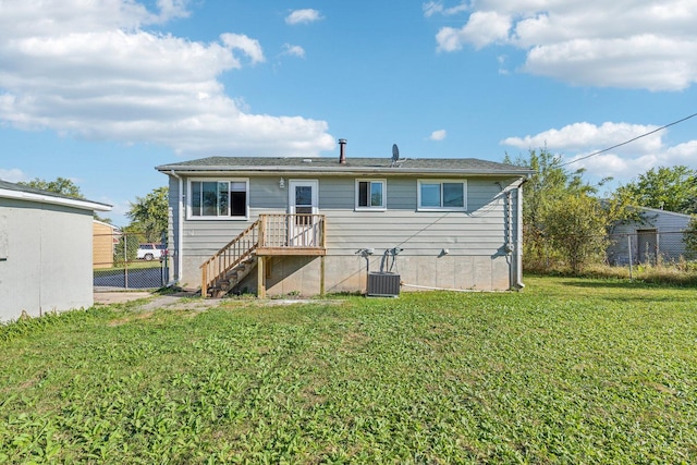 rear view of house featuring central air condition unit and a lawn