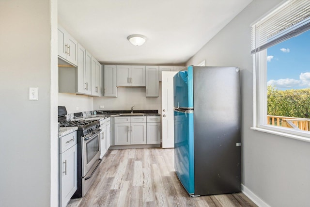 kitchen featuring plenty of natural light, stainless steel appliances, light wood-type flooring, and sink