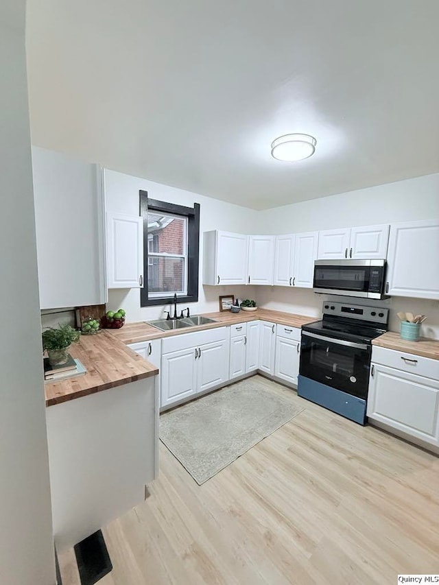 kitchen with stainless steel appliances, butcher block counters, and white cabinets