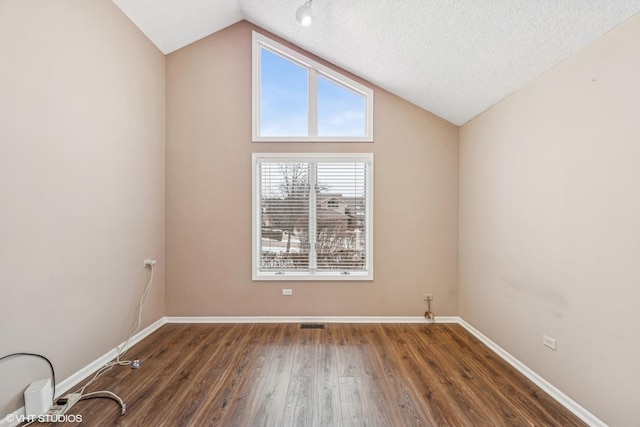 spare room with dark hardwood / wood-style flooring, lofted ceiling, and a textured ceiling