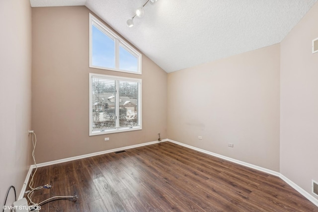 unfurnished room featuring a textured ceiling, dark wood-type flooring, and lofted ceiling