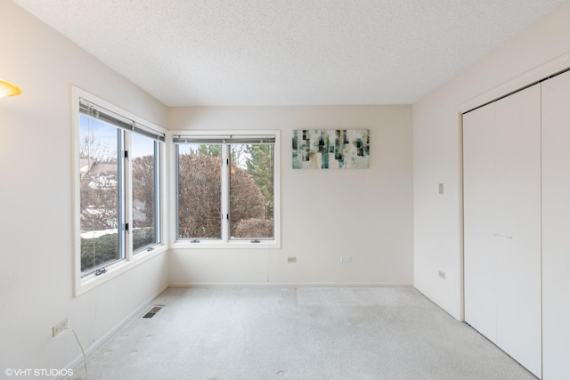 unfurnished bedroom featuring a closet, light colored carpet, and a textured ceiling