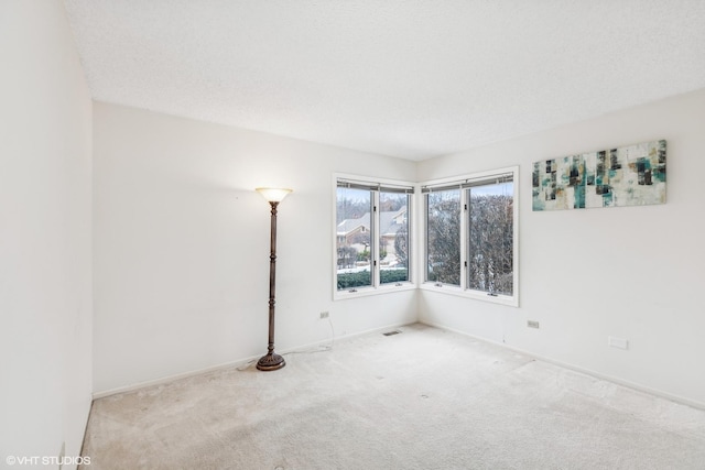 carpeted empty room with a textured ceiling