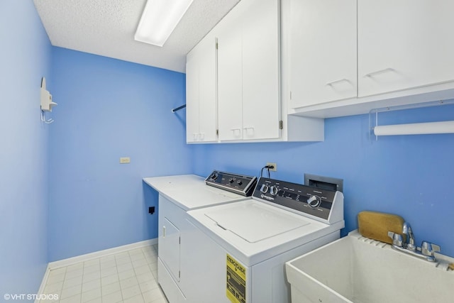 laundry area with a textured ceiling, cabinets, separate washer and dryer, and sink