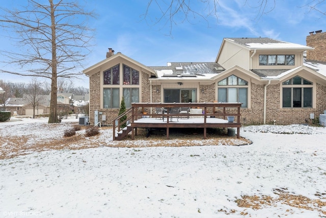 snow covered house featuring central AC and a deck