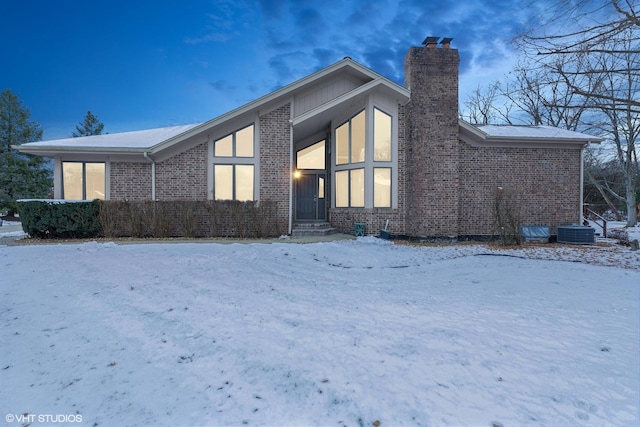 snow covered back of property featuring cooling unit