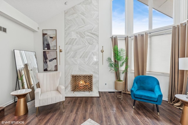 sitting room with vaulted ceiling, a fireplace, and dark wood-type flooring