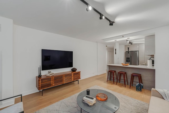 living room with light wood-type flooring and rail lighting